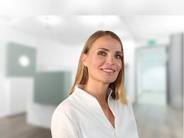 Lächelnde Frau im hellen Praxisbereich des Zahn- und Implantatzentrums Dr. Ghaussy & Partner